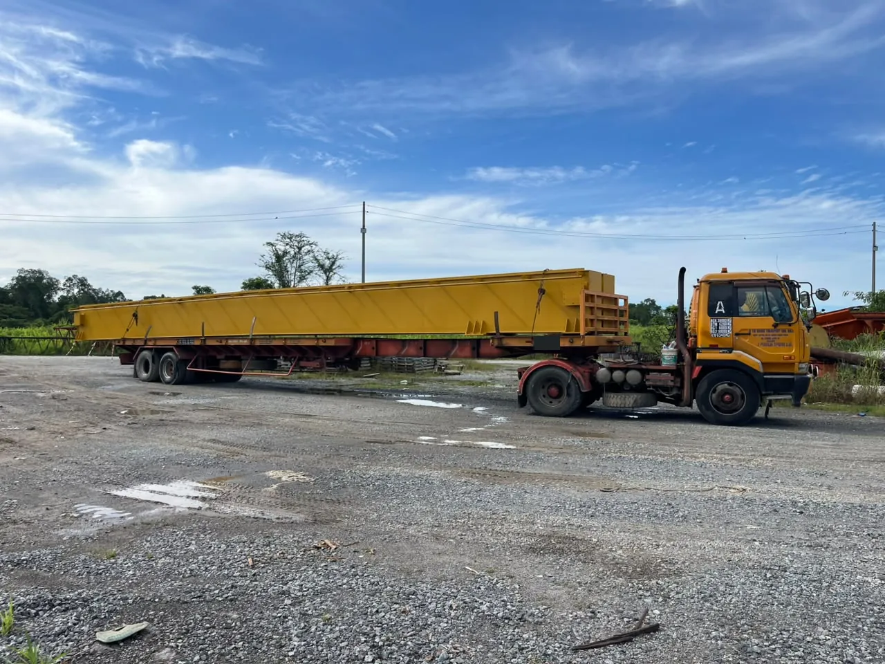 Side view of a yellow girder loaded on an extended trailer