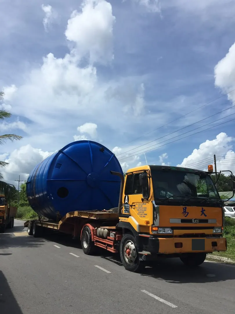 Yellow truck transporting a large blue cylindrical tank